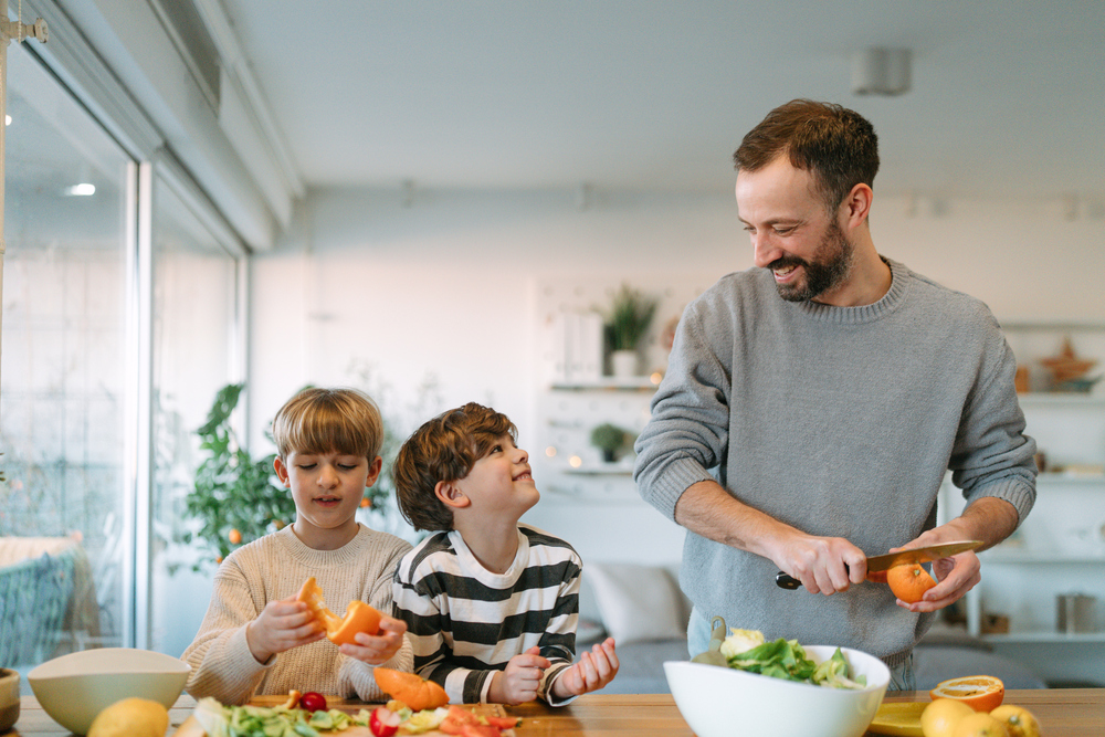 Ein Vater kocht mit seien zwei Kindern gemeinsam